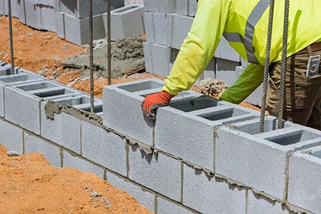 A Mason is in the Process of Mounting a Wall of Aerated Concrete Blocks